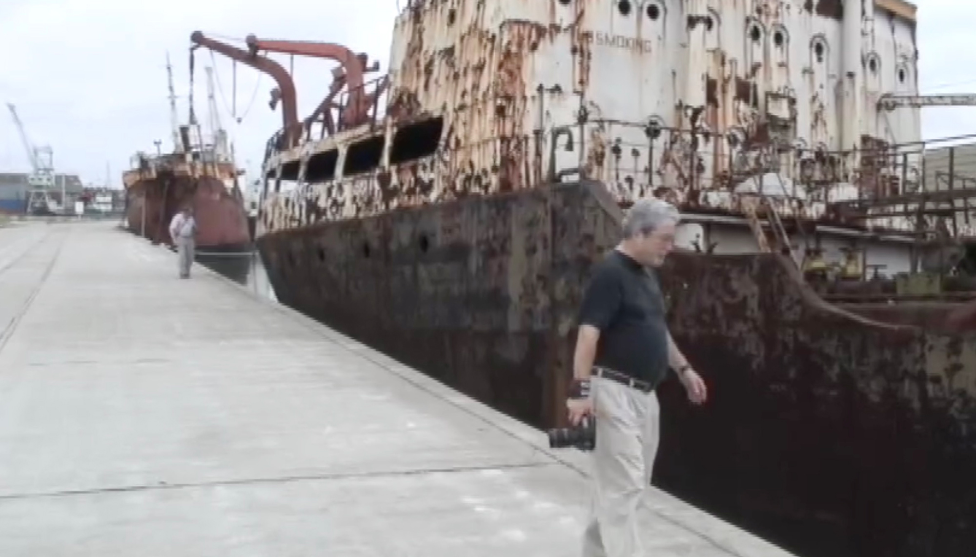 Kevin Raber in the background and Michael Reichmann in the foreground walk along several abandoned ships in the La Boca section of Buenos Aires.