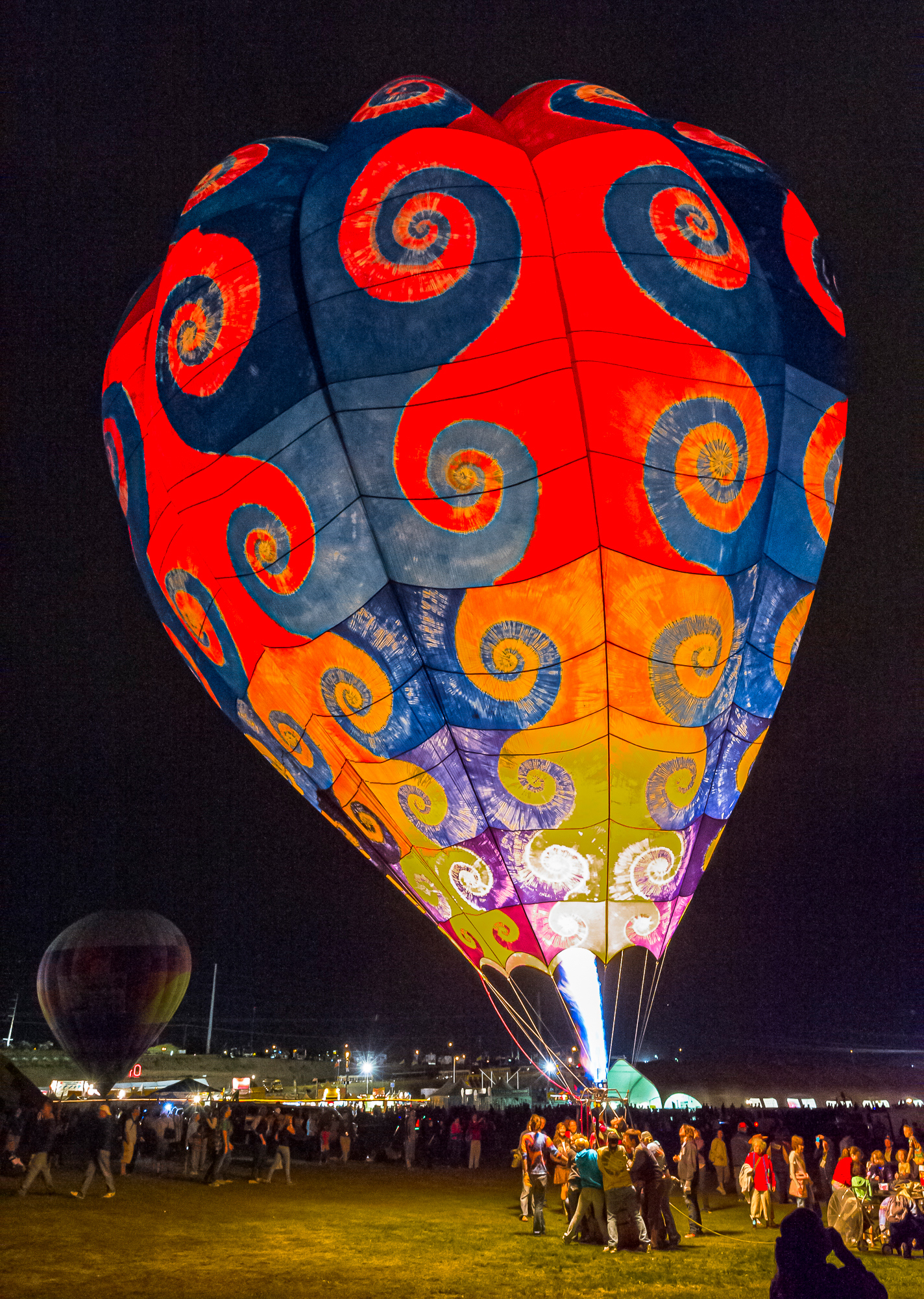 A brilliant hot air balloon fires up at night for public viewing
